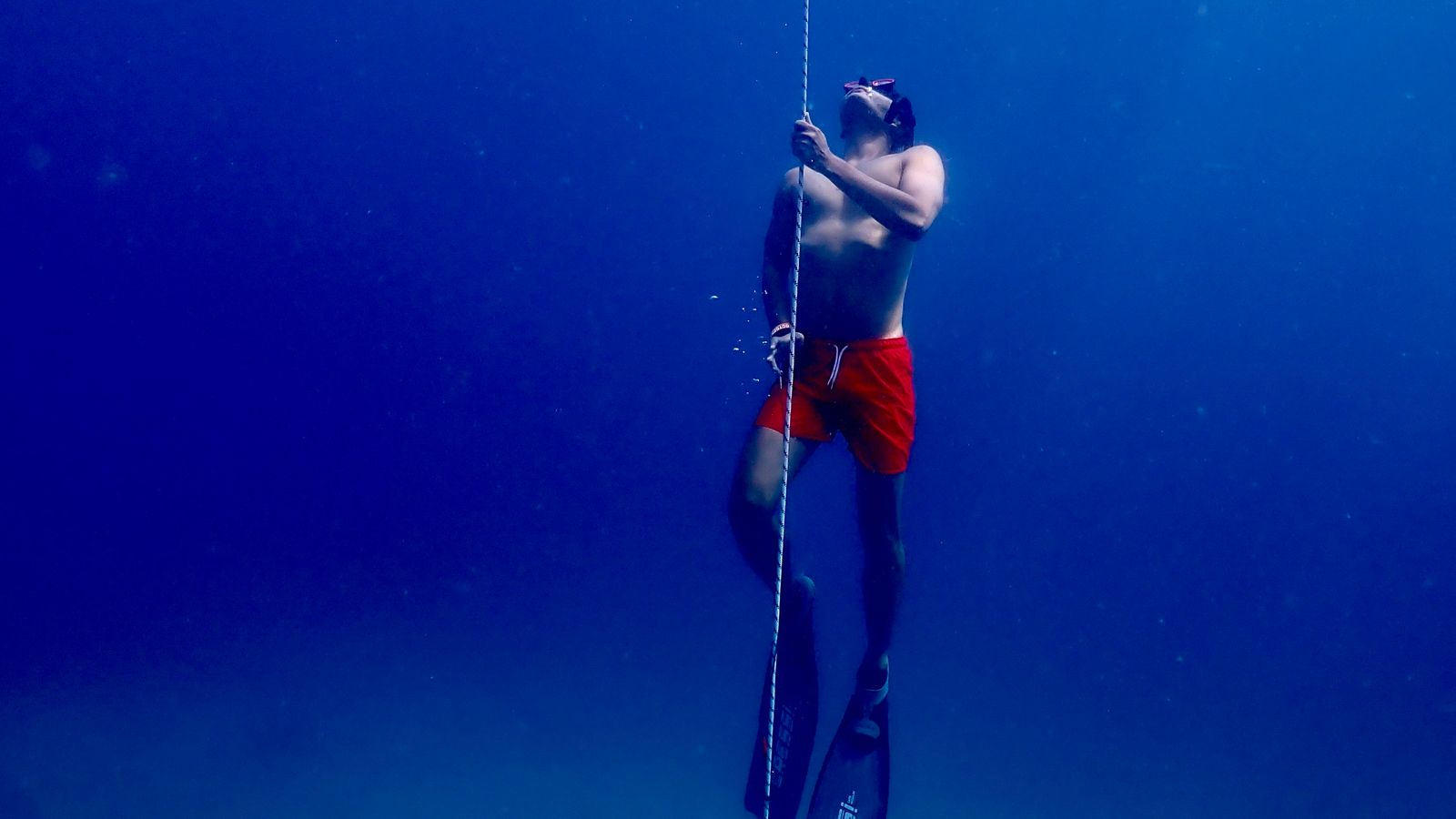 Freediver training on a dive line while wearing long bifins